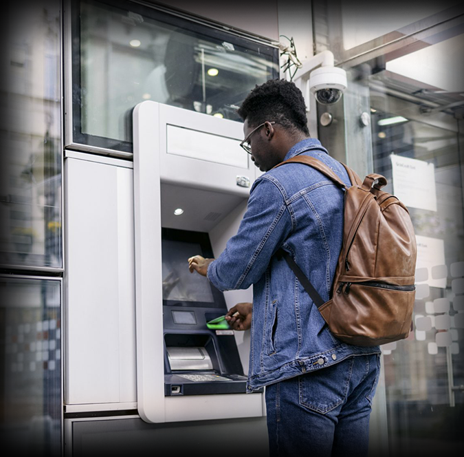 Male traveler with backpack withdrawing cash from an ATM abroad
